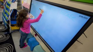 Young student writes on a smart board