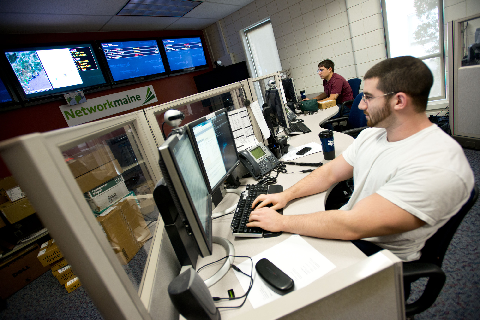 students on computers in front of wall of screens