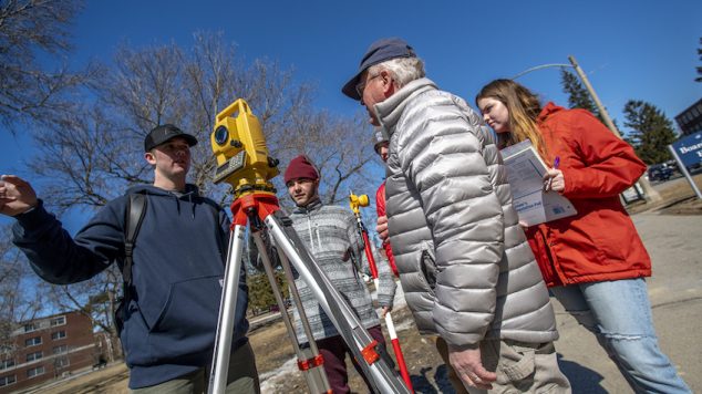 students and instructor outside using surveying equipment