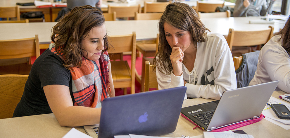 2 students looking at laptop in library