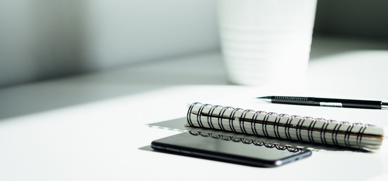 Mobile phone beside pen resting on notepad