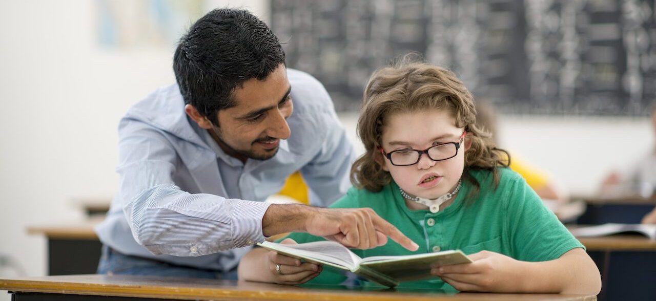 A teacher assisting a young student with a disability