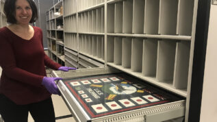 A person pulling a document out of a drawer in an archive.