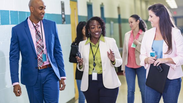 Multiracial group of teachers walking in school hallway
