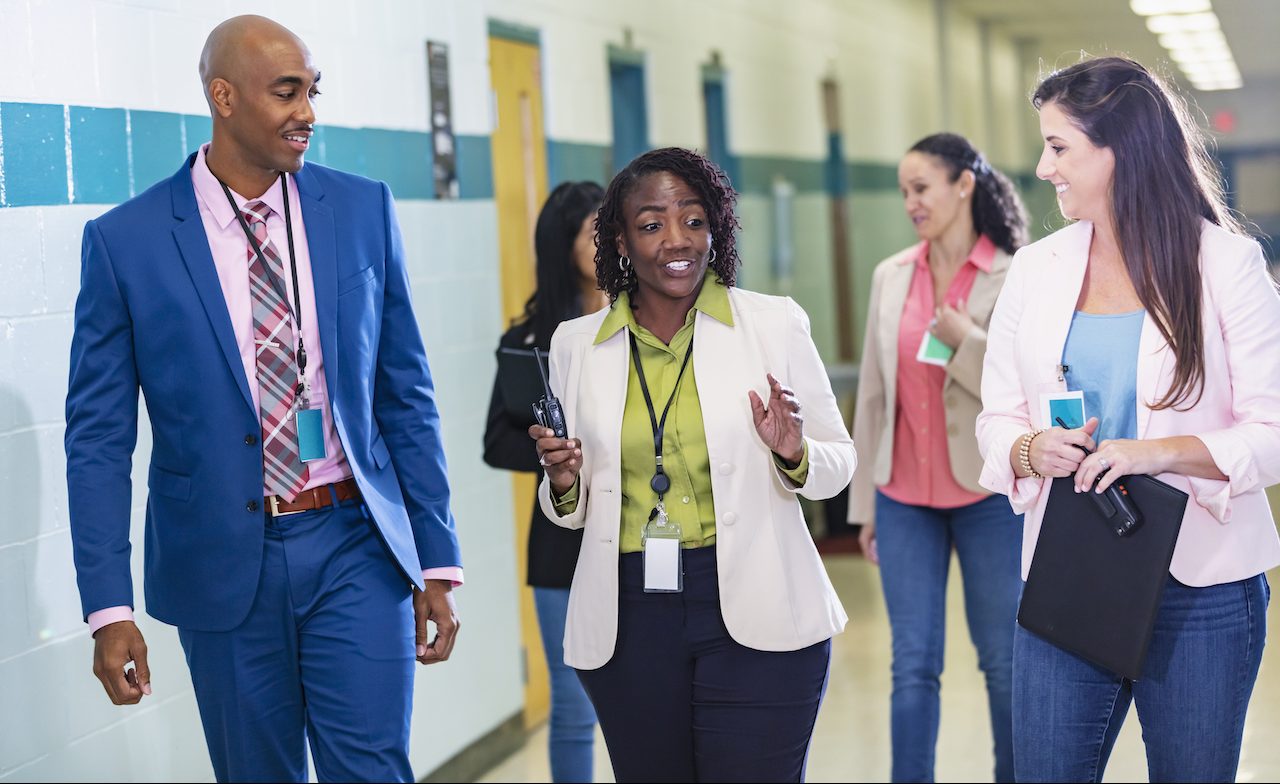 Group of teachers walking in school hallway.