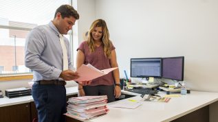 Two office workers looking over files in an office