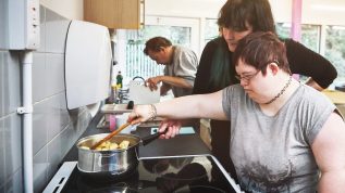 Teacher helping a student with disabilities learn to cook