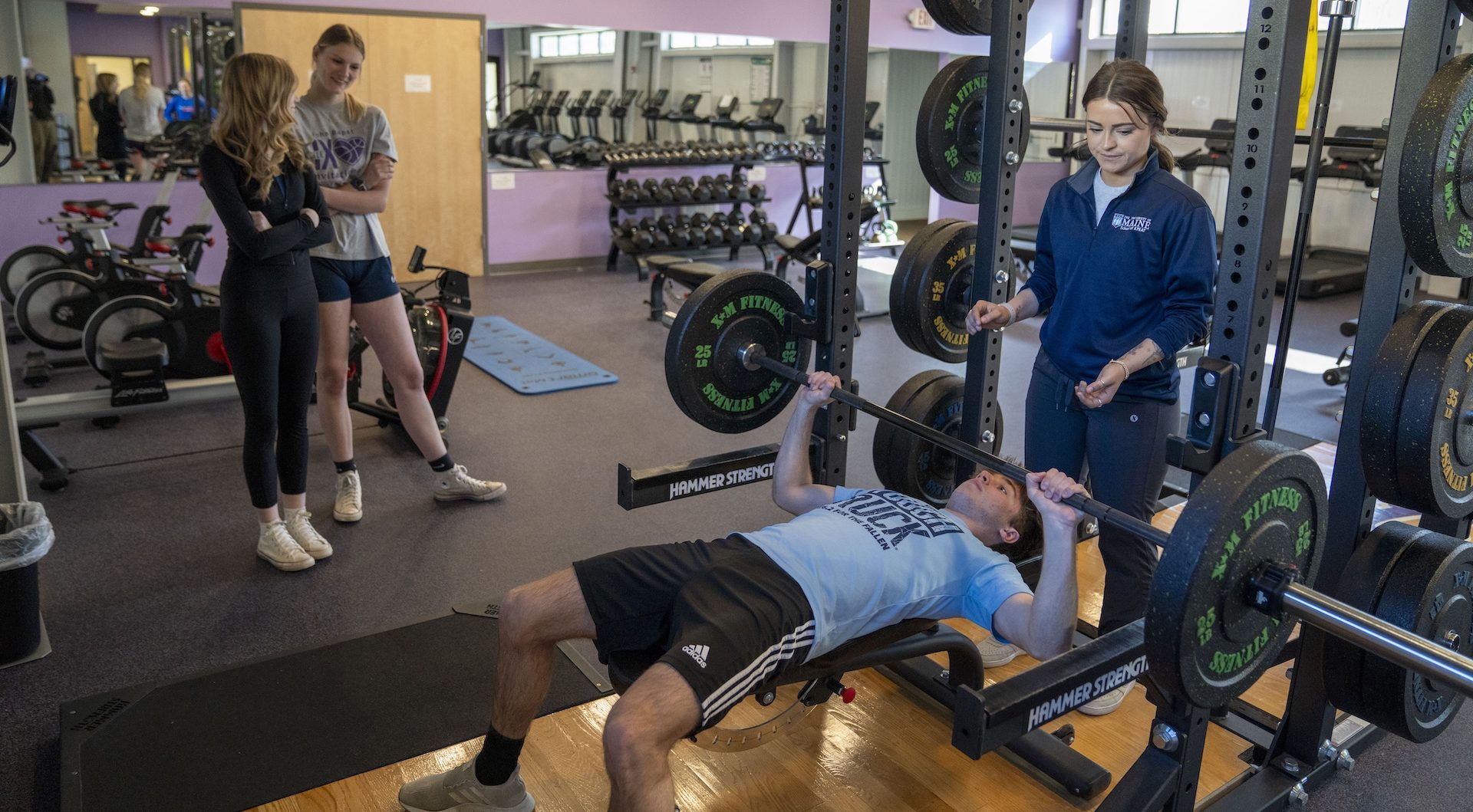 Teacher helps a student in the weight room
