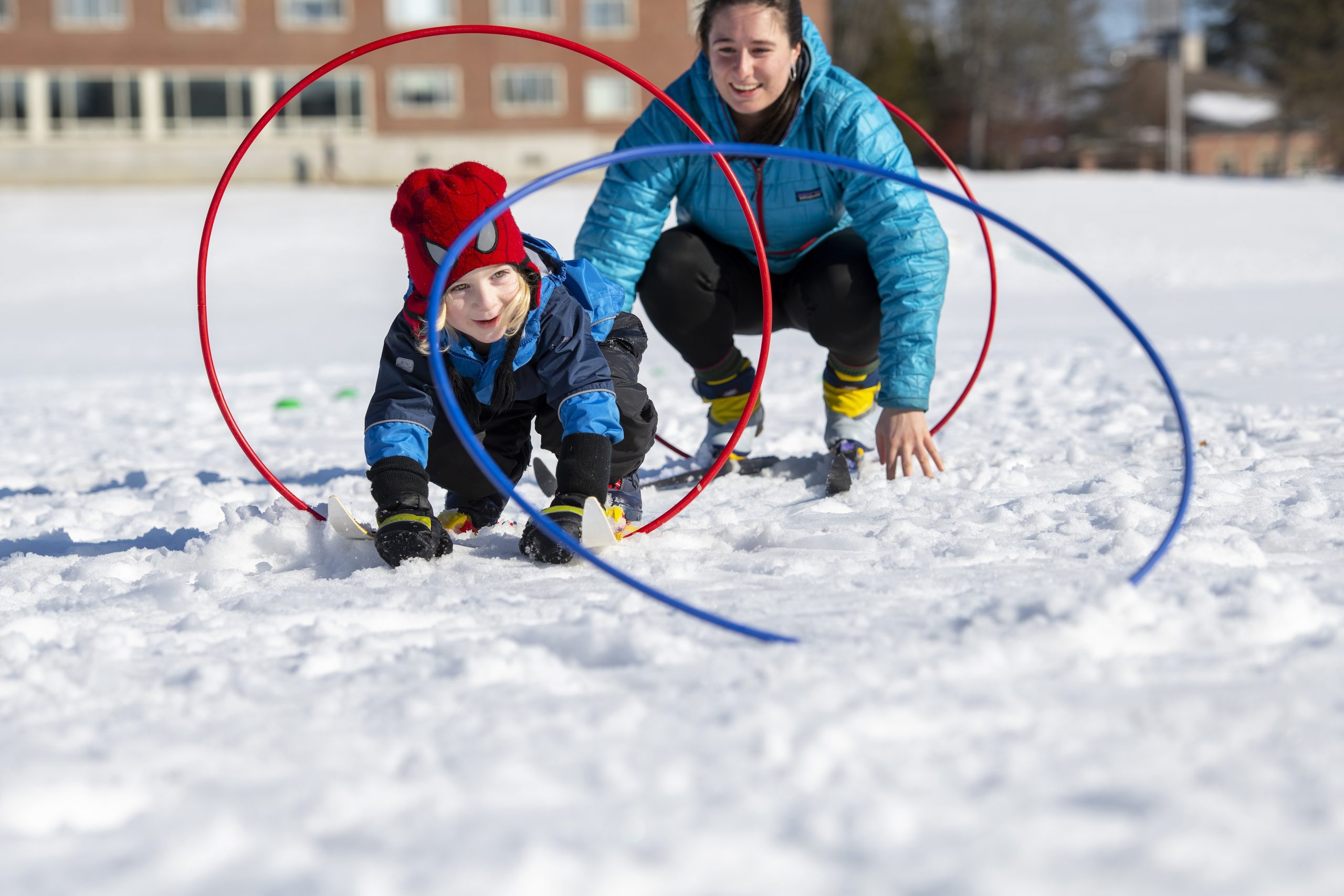 Teacher encouraging preschool student playing in the snow.