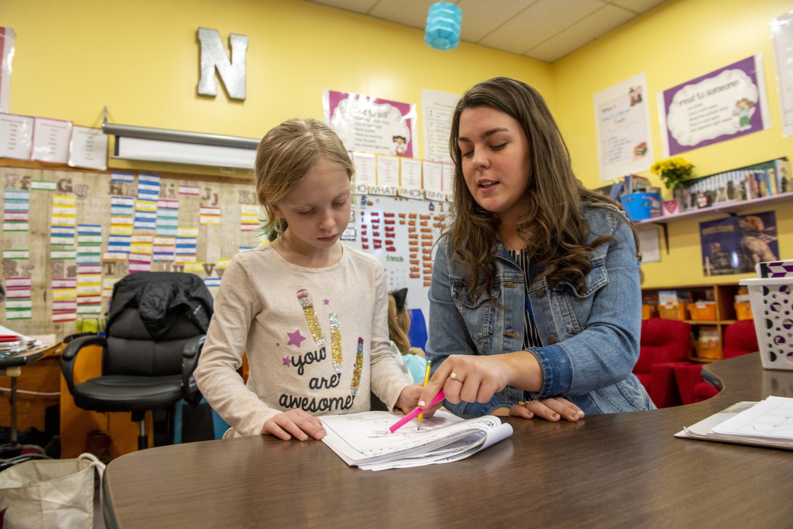 Teacher reading with student in classroom