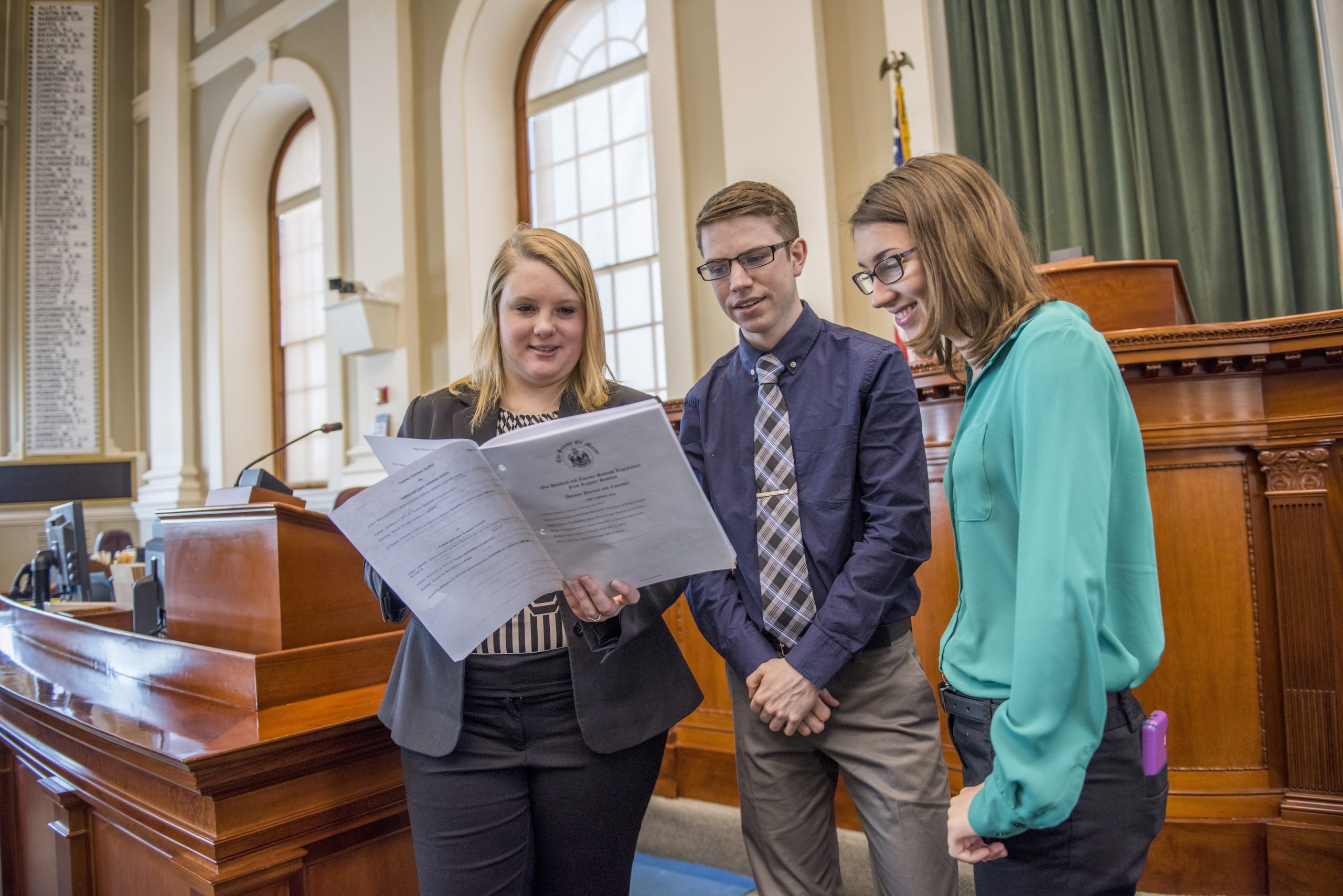 Two students talking with a Maine State Representative in the Maine Capital building