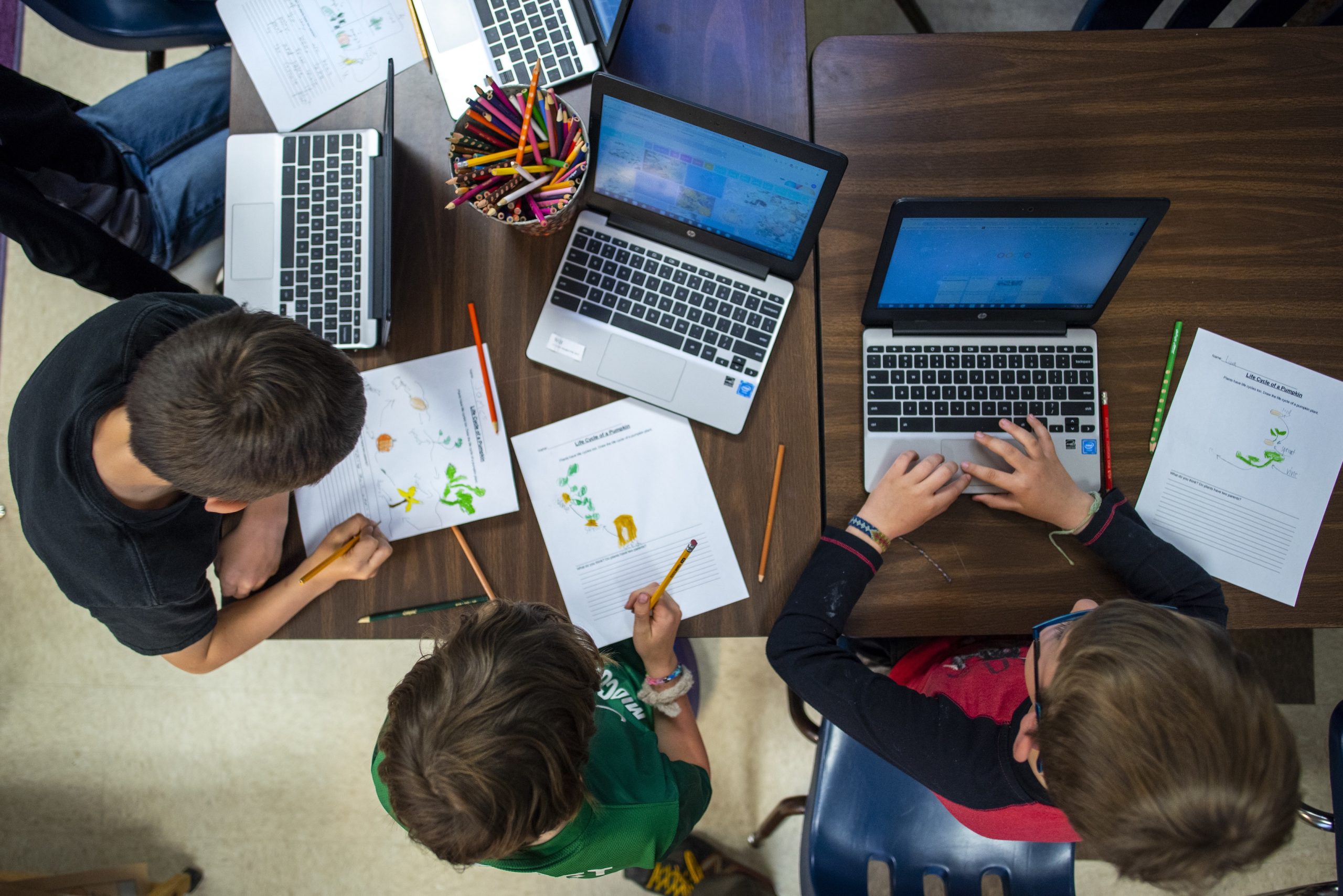 Group of students woking on laptops and a worksheet