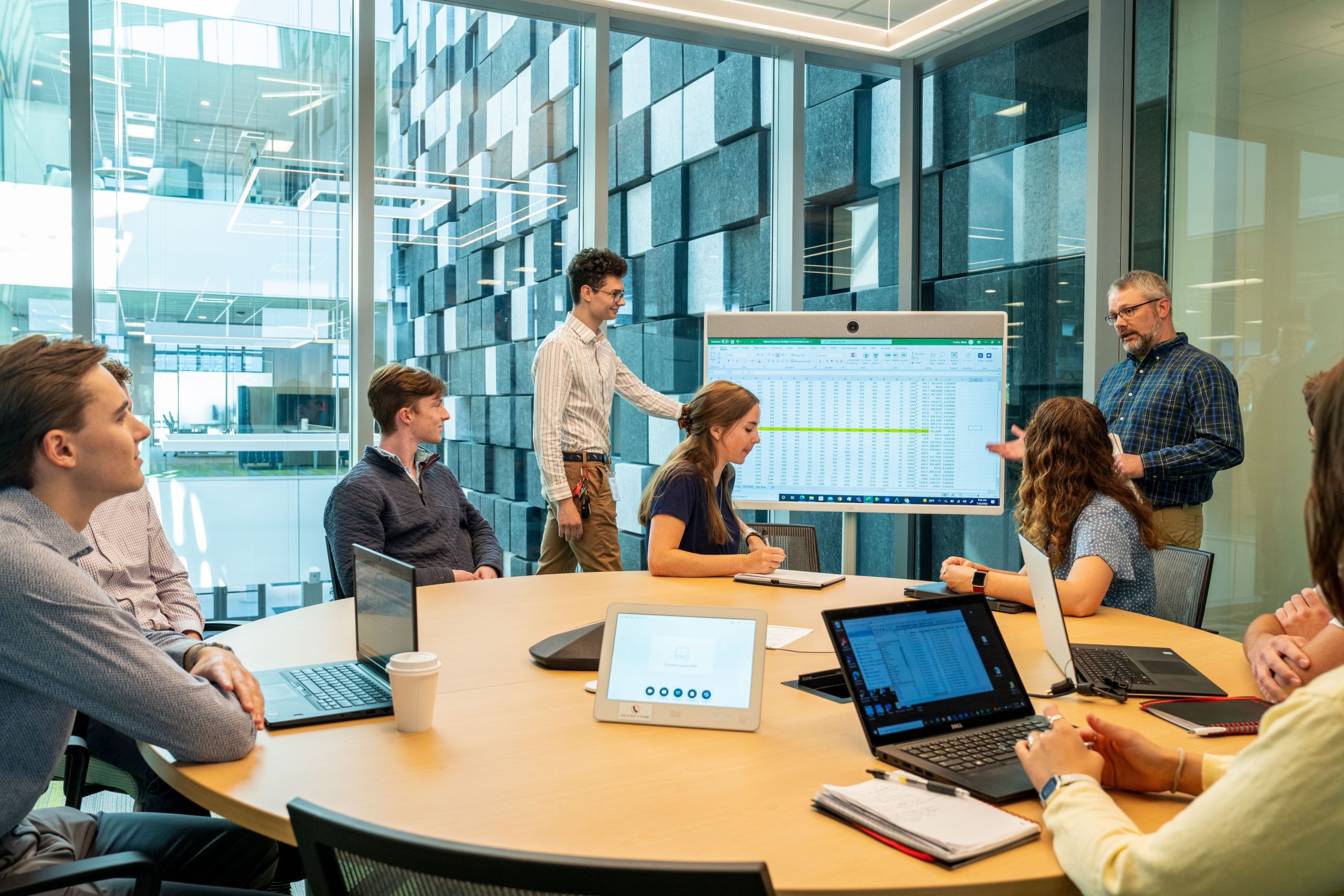 Business people in meeting with an excel spreadsheet on a large screen