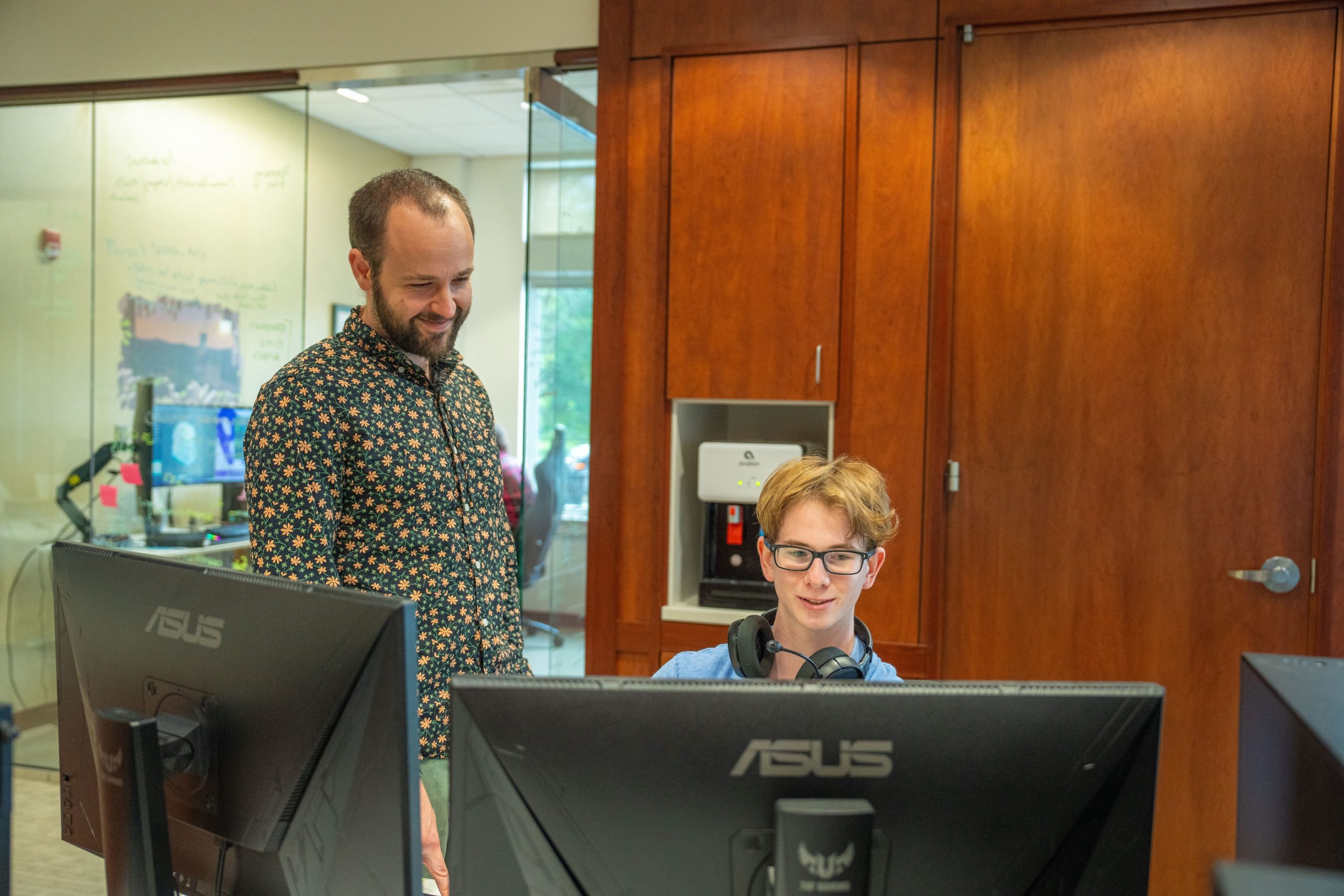 A teacher working with a student using a computer.