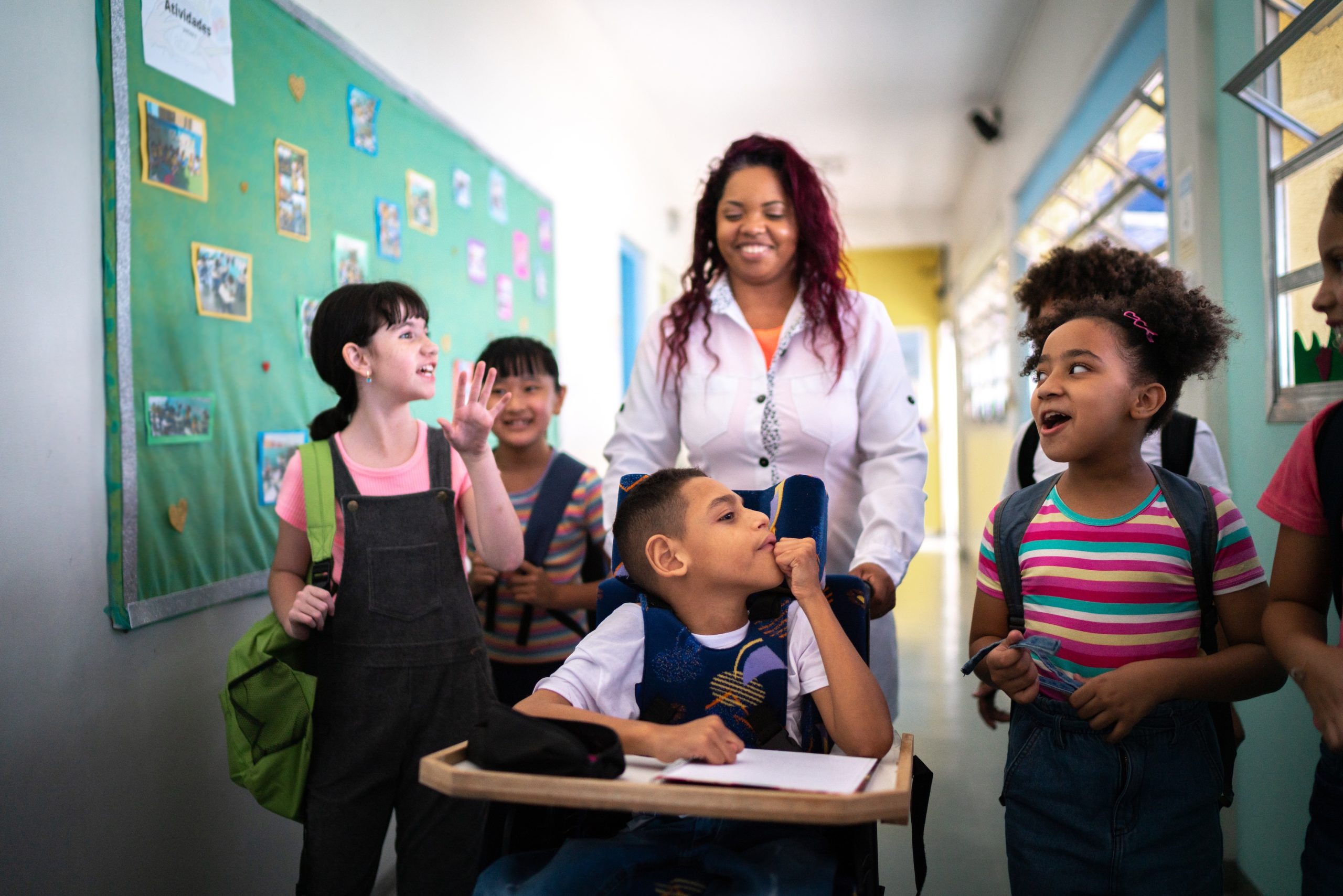 A teacher walking down a hallway with students including a student with special needs.