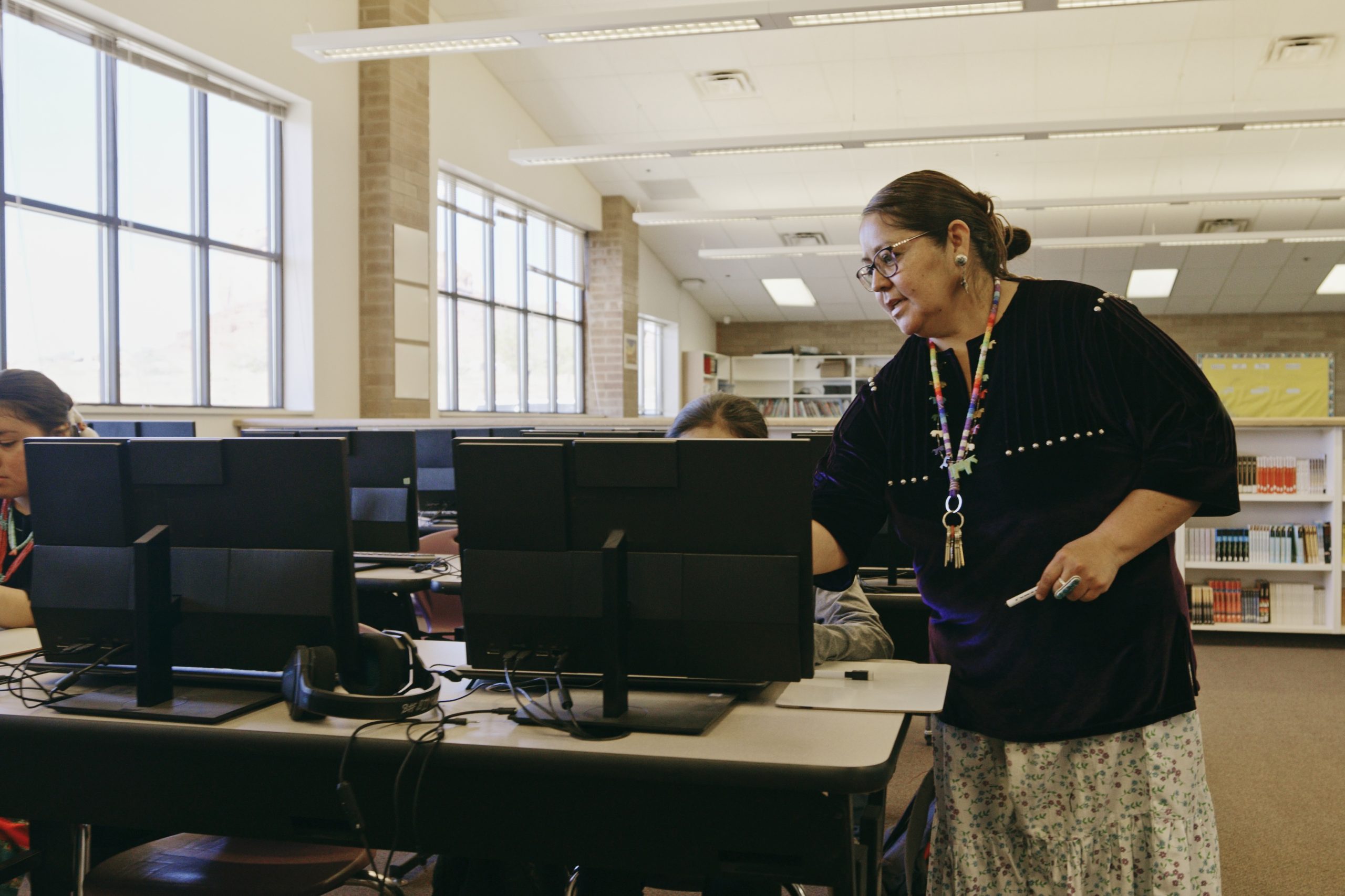 A teacher working with students using computers.