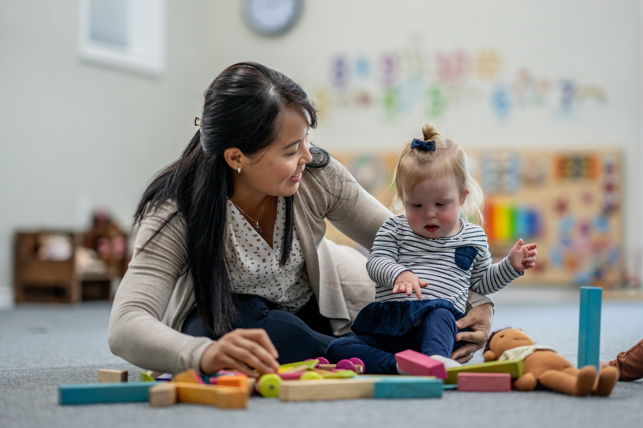 A teacher playing with a toddler with special needs.