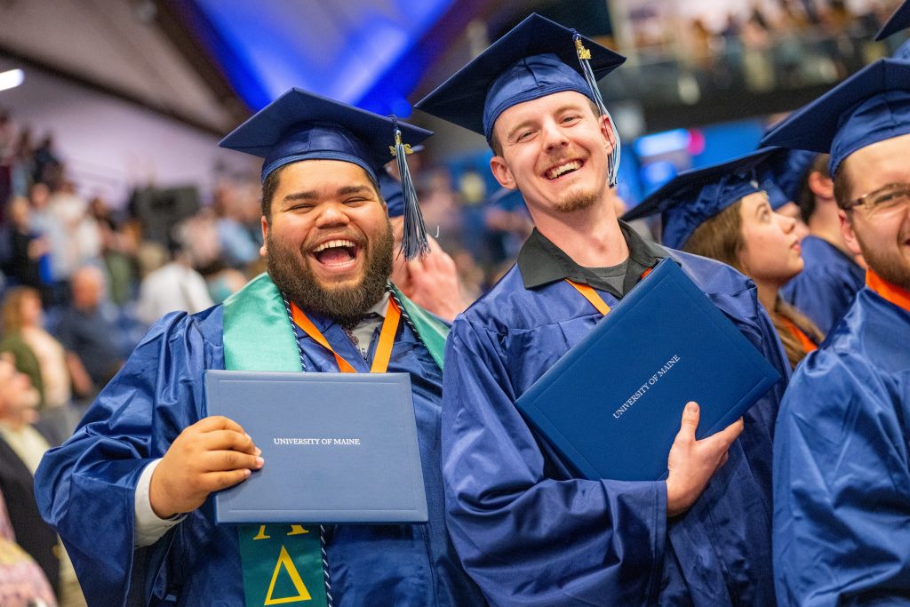 Two graduates smiling at graduations