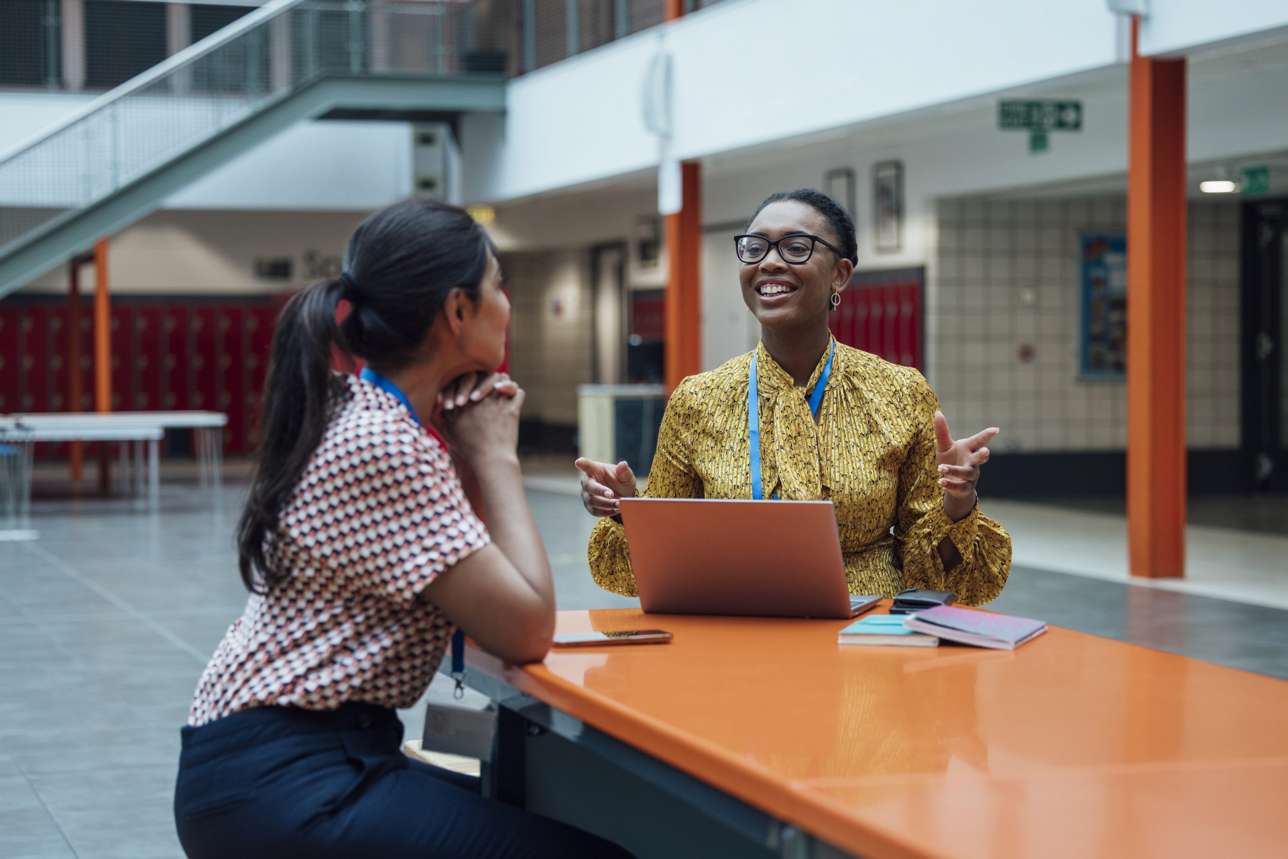 Two teachers talking in a cafeteria