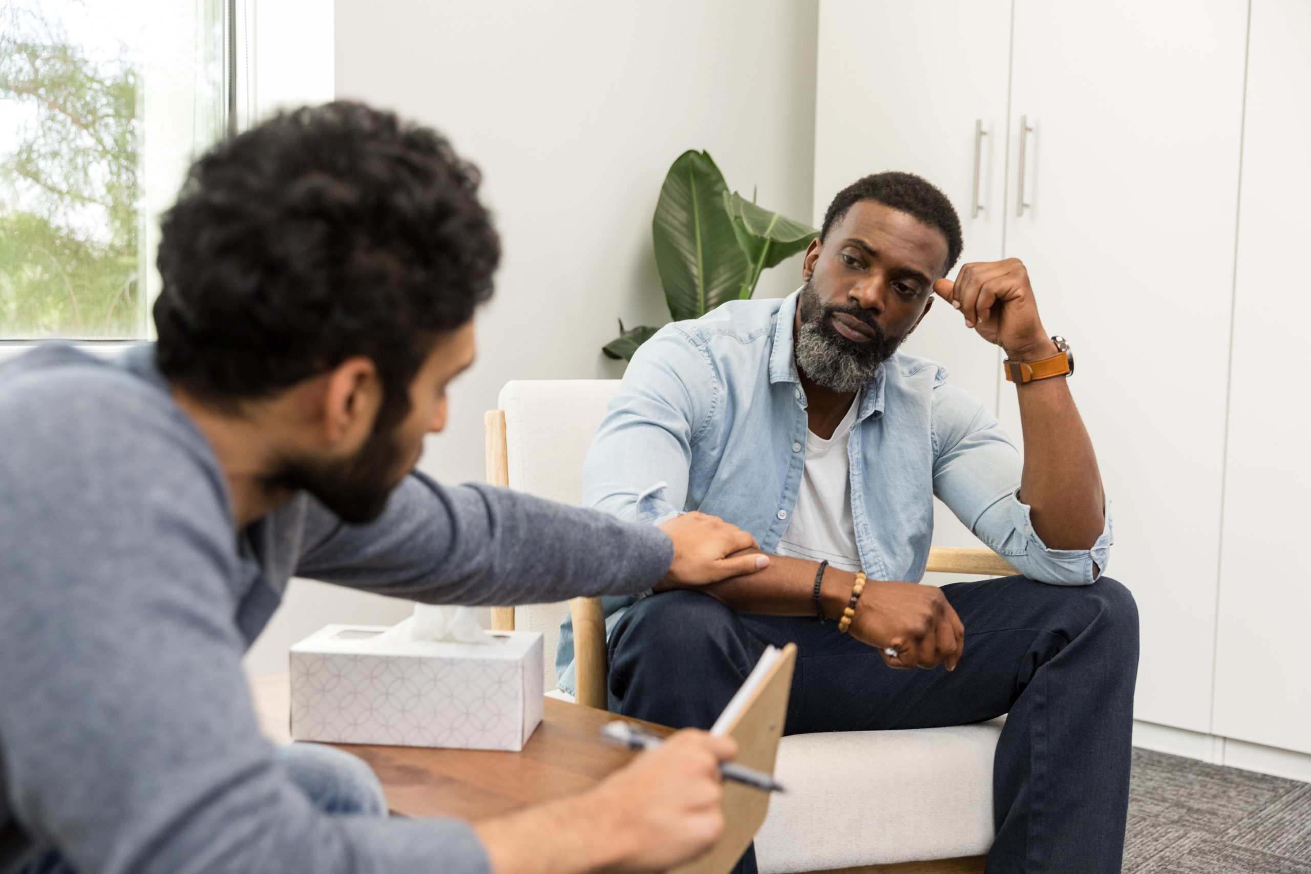 The therapist puts a reassuring hand on an emotional client